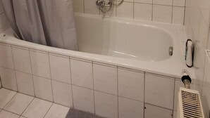 A bathroom with a bathtub, shower, and a toilet.
