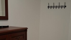 A corner room with a wooden dresser, tiled floor, and a coat rack on the wall.