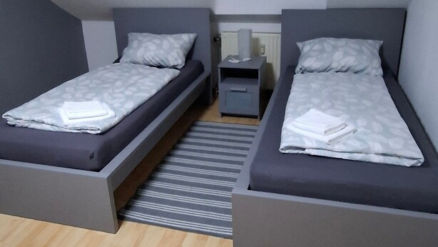 A bedroom with two beds, a window, and a radiator.
