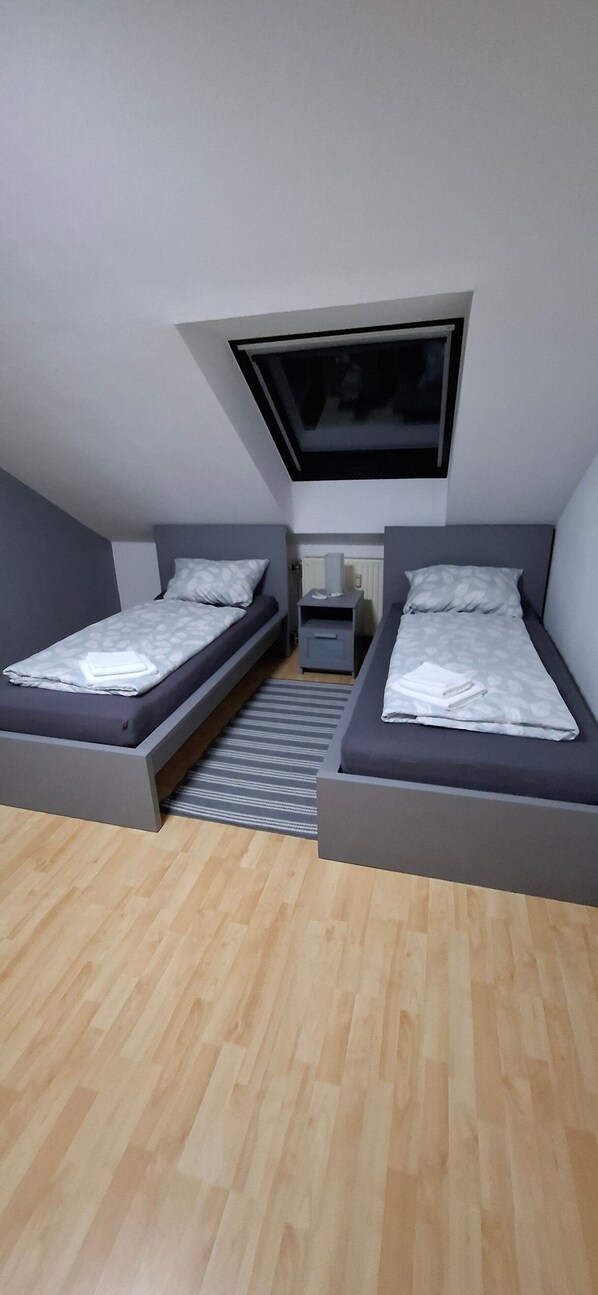 A bedroom with two beds, a window, and a radiator.
