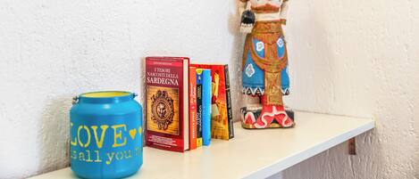 Una estantería con libros, un adorno y un recipiente azul con texto.