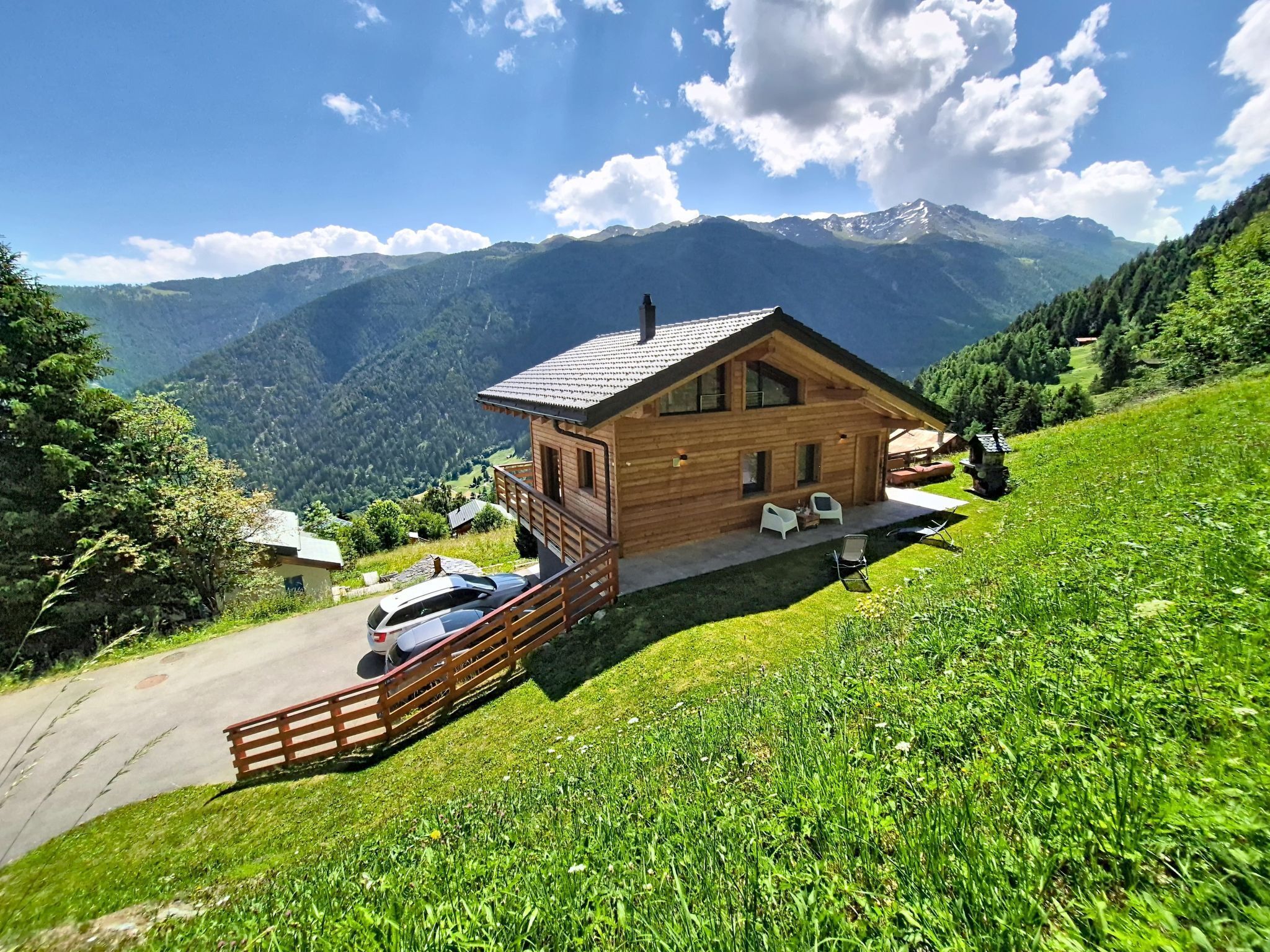 A wooden cabin with a balcony, a car parked in front, and a mountain view.