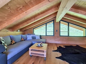 Ein gemütliches Schlafzimmer im Loft-Stil mit Holzbalkendecke, einer Couch, einem Couchtisch und einem großen Fenster.