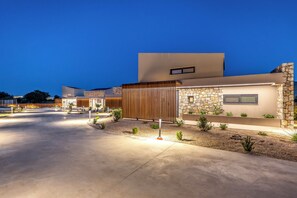A modern residential building with a stone facade, a flat roof, and a well-lit driveway. - Orama Sunset | Ammi Villa (Rhodes)