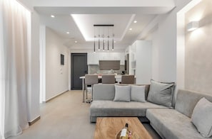 Ein modernes Wohnzimmer mit einer Couch, einem Couchtisch mit einer Flasche und einem Essbereich im Hintergrund.