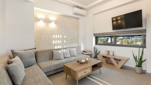 A modern living room with a sofa, coffee table, and a TV mounted on the wall. - Orama Sunset | Ammi Villa (Rhodes)