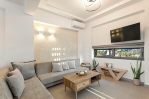 A modern living room with a sofa, coffee table, and a TV mounted on the wall. - Orama Sunset | Ammi Villa (Rhodes)