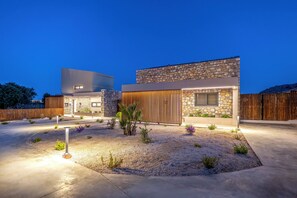 A modern house with a stone facade, a wooden fence, and a landscaped garden. - Orama Sunset | Ammi Villa (Rhodes)