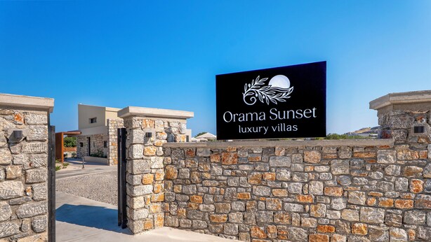 A sign for Orama Sunset luxury villas with a stone wall and a clear sky. - Orama Sunset | Ammi Villa (Rhodes)