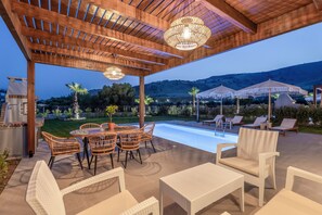 A covered outdoor area with a pool, wicker furniture, and umbrellas. - Orama Sunset | Ammi Villa (Rhodes)