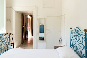 Ein Schlafzimmer mit Bett, Stuhl, Schminktisch und Spiegel.