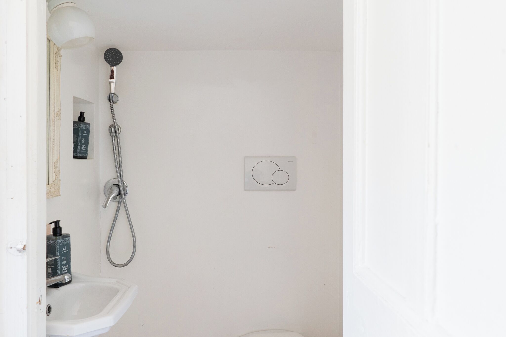 Ein Badezimmer mit Dusche, Waschbecken und einer wandmontierten Bedienkonsole.