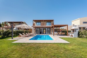 Une maison moderne dotée d’une piscine, de chaises longues et d’un espace salon extérieur.
