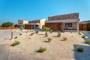 Un bâtiment moderne avec une façade en pierre, une clôture en bois et une cour recouverte de gravier, agrémentée de petites plantes.