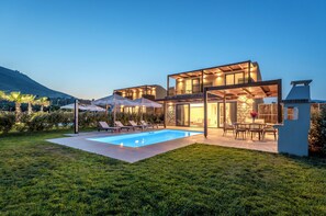 A modern house with a swimming pool, outdoor seating, and a dining area. - Orama Sunset | Stela Villa (Rhodes)
