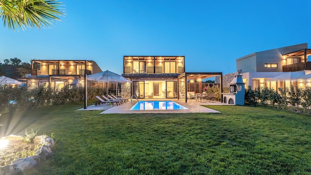 A modern house with a swimming pool, outdoor seating, and a well-maintained lawn. - Orama Sunset | Stela Villa (Rhodes)
