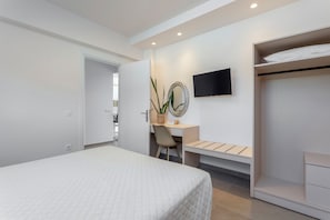 A modern hotel room with a bed, a desk, a chair, a television, and a wardrobe. - Orama Sunset | Stela Villa (Rhodes)