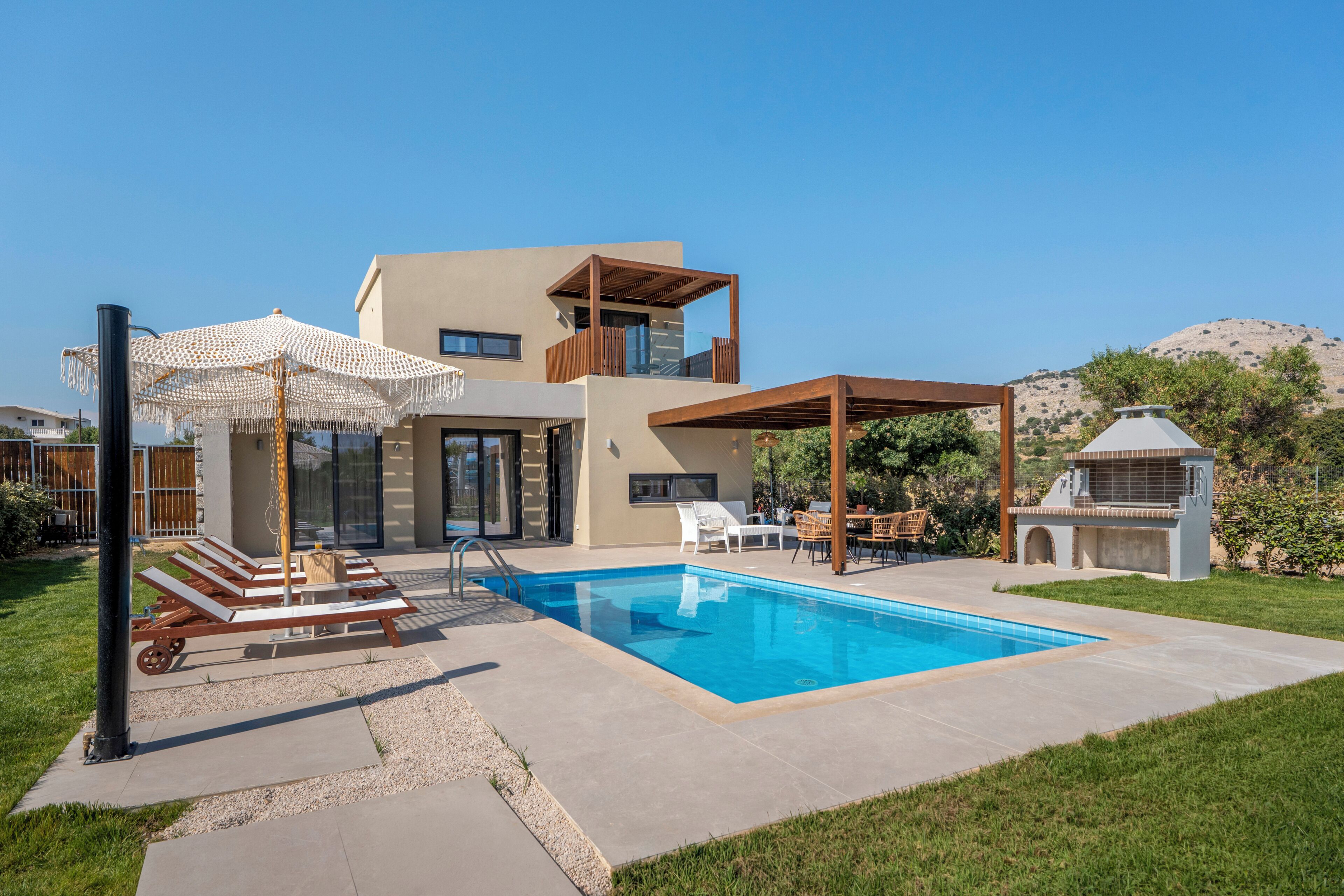 Een modern huis met een zwembad, terras en een barbecuehoek.