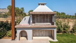 A barbecue grill with a chimney, brick base, and a metal roof. - Orama Sunset | Joana Villa (Rhodes)