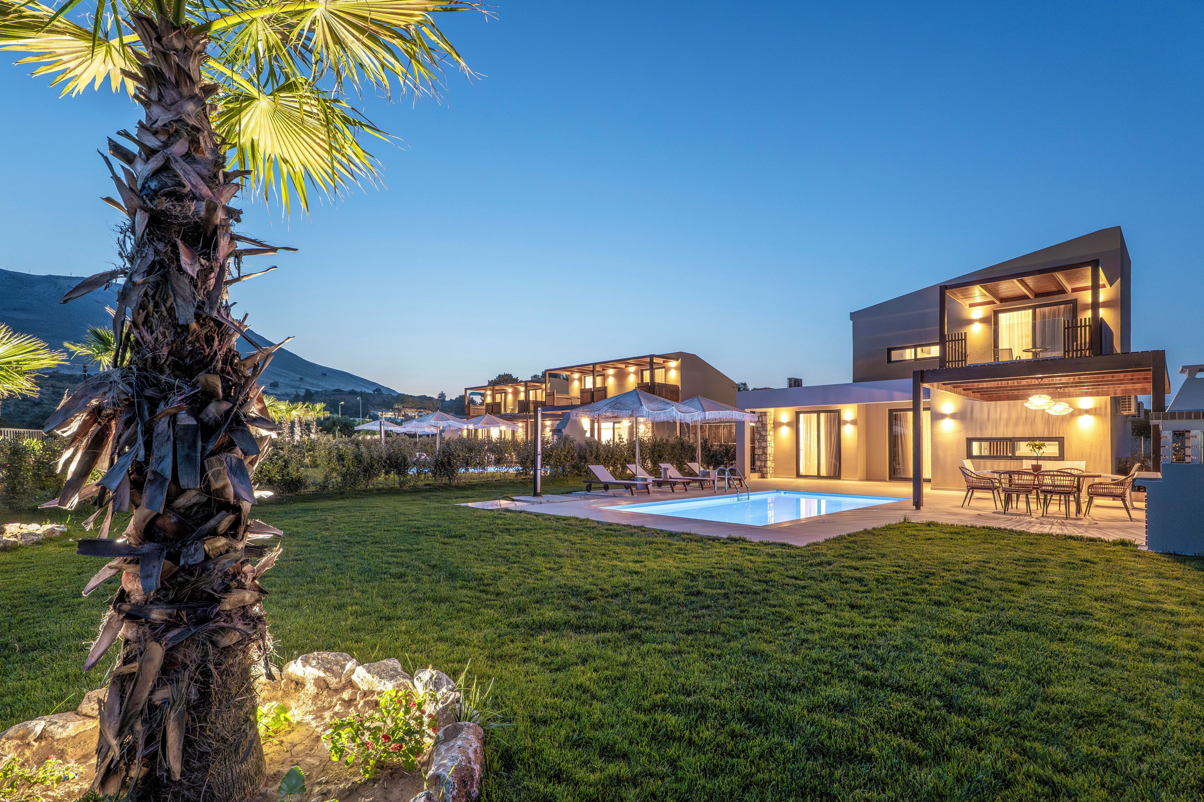 A modern house with a swimming pool, outdoor seating, and a well-maintained lawn.