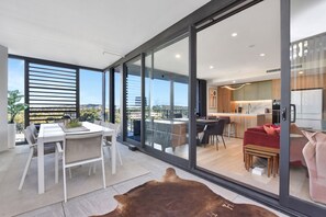 Et moderne interiør med spiseplads, køkken og skydedøre til en balkon.
