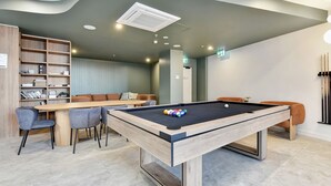 A billiards table with balls, a pool table, and a seating area with chairs and a sofa. - Newcastle Views at One Apartments (Newcastle West)