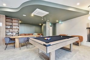 Ein Billardtisch mit Kugeln, eine Sitzgruppe mit Stühlen und einer Couch.