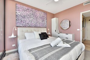 Ein Schlafzimmer mit einem großen Bett, einem Nachttisch, einer Kommode, einem Spiegel und einem Wandbild.