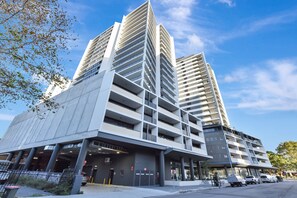 A modern multi-story building with a parking garage entrance, large windows, and a flat roof. - Newcastle Views at One Apartments (Newcastle West)