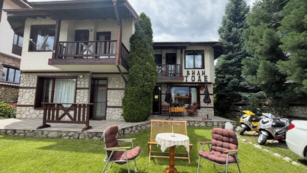 A two-story building with a balcony, outdoor seating, and a sign reading 'ВИН ТОЕ'.