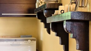 A kitchen with wooden shelves holding dishes, a coffee maker, and a microwave.