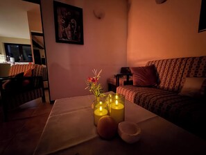 A cozy room with a table set for tea, featuring a vase with flowers and candles.