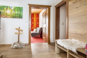 Ein Zimmer mit einem Bett, einem Holzschrank, einem Waldgemälde, einem Wegweiser und einem kleinen Steinbruch.