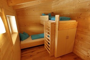 Ein Holzhäuschen-Zimmer mit Etagenbett, einem kleinen Schrank und einem Fenster.