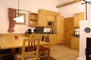 Eine Küche mit Holzausstattung, einer Mikrowelle und einem Esstisch mit Stühlen.