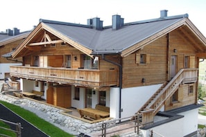 Eine Holzchalet mit Balkon, einer Treppe und einer Steinmauer.