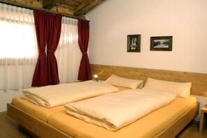 A double bed with a wooden headboard, a nightstand, and two framed pictures on the wall. - Chalet in Hochkrimml for 6-14 people (Krimml)