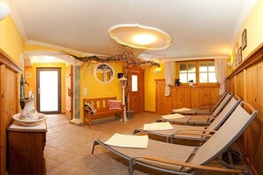 Ein Zimmer mit Holzwänden, einer Bank und vier Liegestühlen mit Handtüchern.