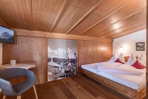 Ein Zimmer mit Holzwänden, einem Bett, einem Schreibtisch und einem Stuhl.