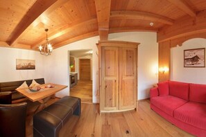 Ein Holzinnenraum mit Esstisch, Bank, rotem Sofa und Holzschrank.
