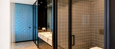 Un baño moderno con cabina de ducha de vidrio, tocador de mármol y un inodoro.