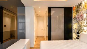 A modern bedroom with a bed, a bedside table, a mirror, and a wall with a decorative panel.