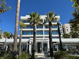A modern building with a glass facade, palm trees in front, and a sign for a restaurant.