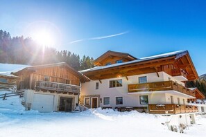 Een chalet met meerdere verdiepingen, houten gevel, balkon en garage.