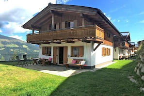 Ein Chalet mit Balkon, einer Sitzgelegenheit auf der Terrasse und Blick auf die Berge.