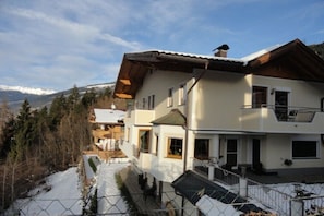 Un bâtiment à deux étages doté d’un balcon, d’un espace extérieur couvert et offrant une vue sur des montagnes enneigées.