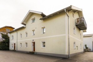Monikerroksinen rakennus, jossa on tasainen julkisivu, parveke ylemmässä kerroksessa ja pieni sisäänkäynti, johon kuuluu portaat.