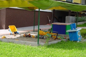 Ein Sandkasten mit Spielzeug und einem gelben Stuhl.