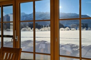 Ein Zimmer mit großen Fenstern und Blick auf eine verschneite Landschaft und Berge.