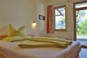 Ein Bett mit Kissen, eine Wandleuchte, ein Fenster mit Vorhängen und ein kleines Bild an der Wand.